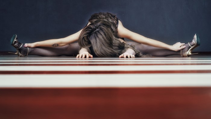 Woman in pantyhose and stilettos doing a split