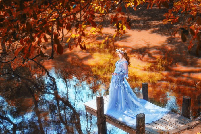 Woman in blue dress on a dock in autumn