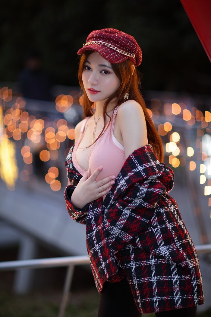 Asian woman wearing a baseball cap and plaid jacket