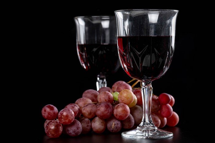 Two glasses of red wine with grapes