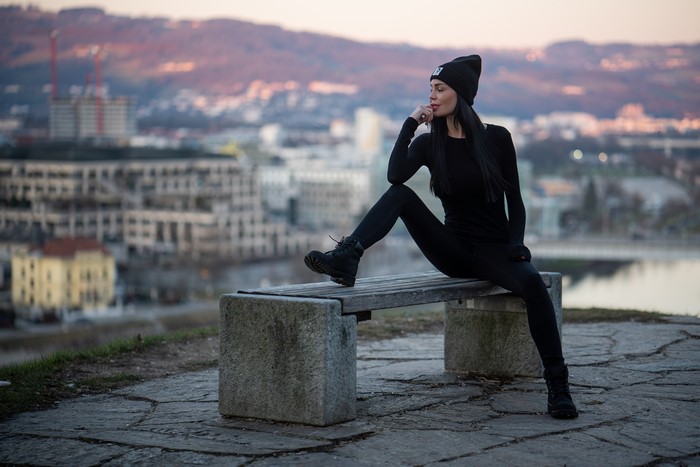 Brunette girl in winter hat sitting on bench