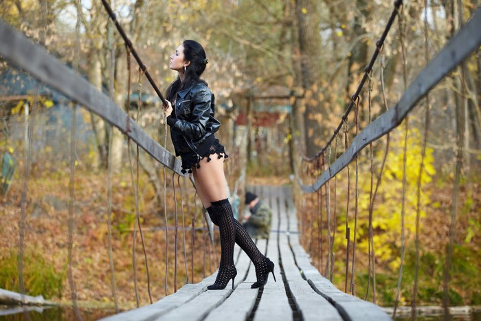 Brunette girl in jacket and stilettos on a bridge