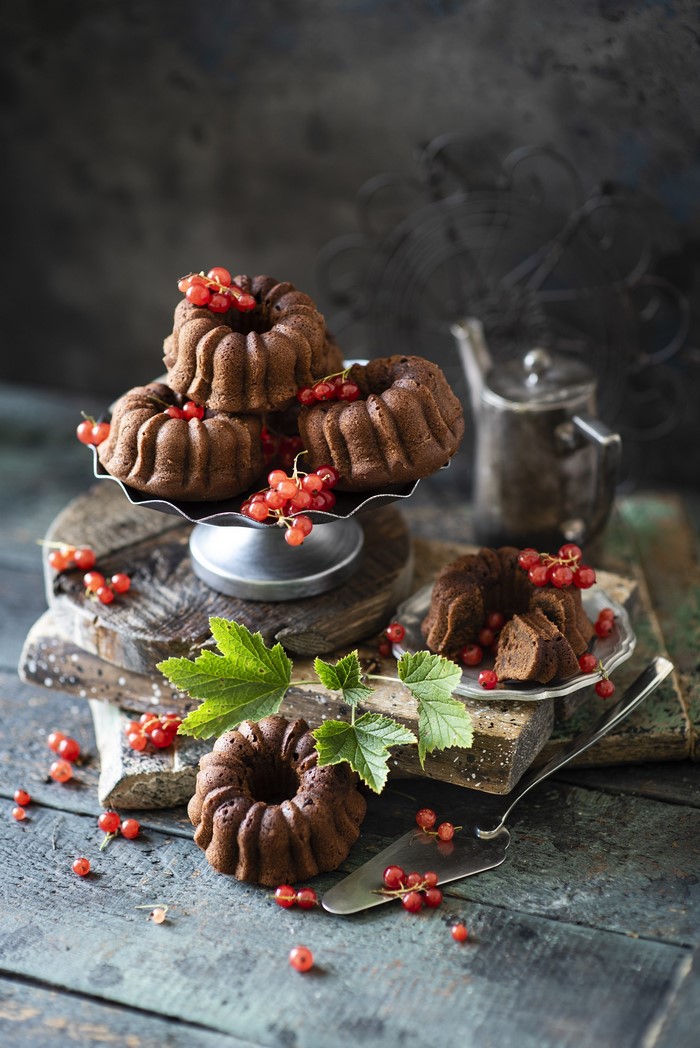 Chocolate bundt cakes with red currants on wooden planks
