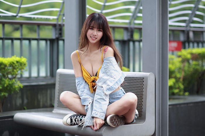 Asian woman with brown hair sitting on a bench