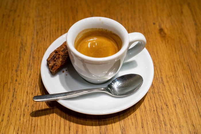 Espresso cup with biscotti and spoon on wooden table