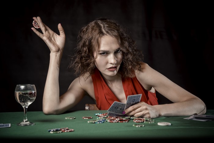 Woman playing cards with casino tokens and a drink