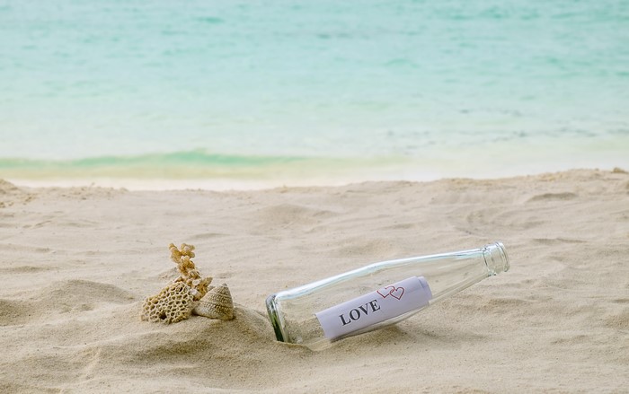 Message in a bottle with the word LOVE on a sandy beach