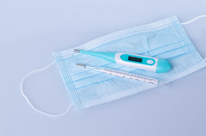 Face mask and thermometers on gray background