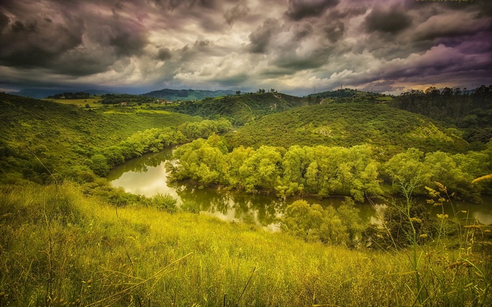 River winding through green hills under stormy sky