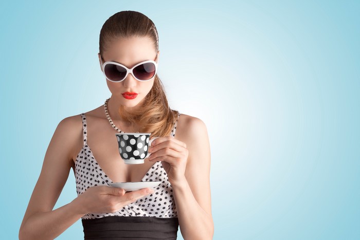 Woman in sunglasses holding a polka dot mug
