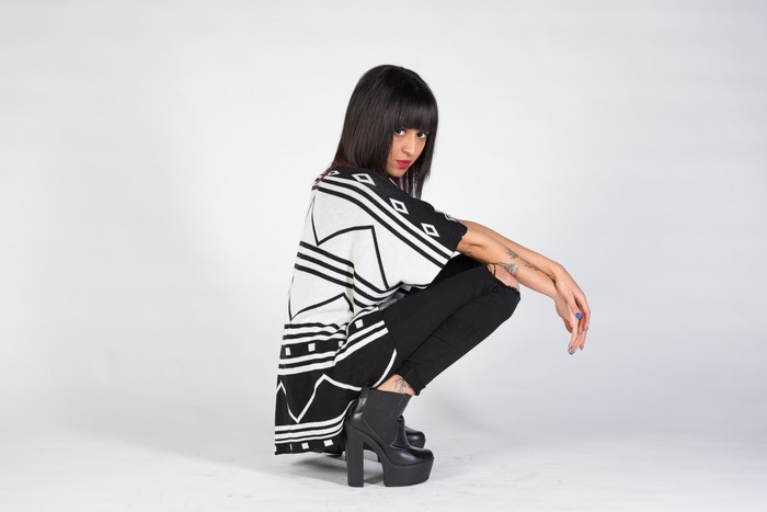 Nadia crouching in a black and white patterned top