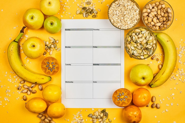 Healthy food items arranged around a weekly planner