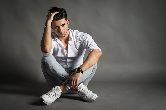 Man in white shirt sitting on gray background