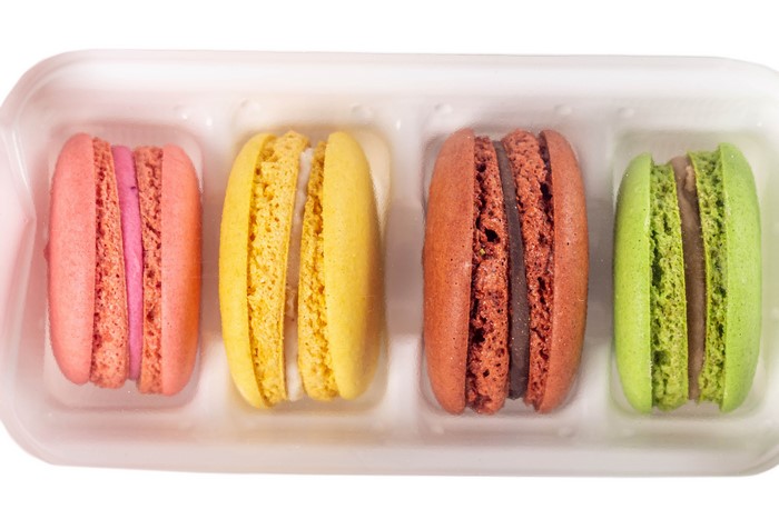 Four colorful macarons in a white tray