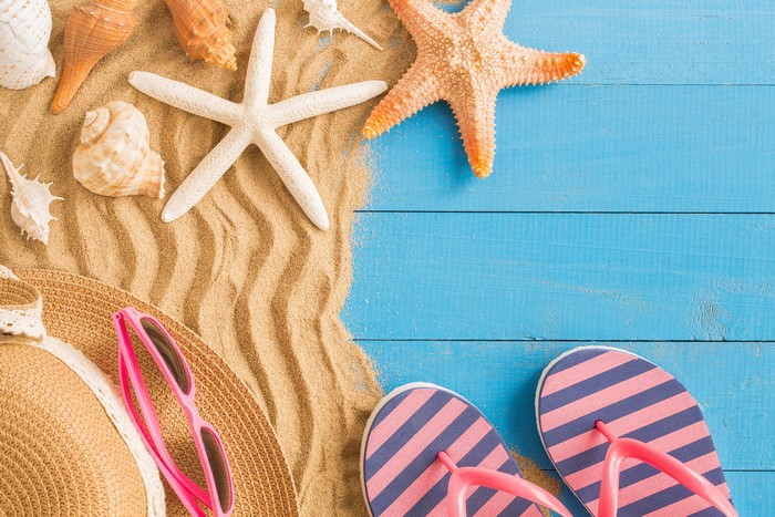 Summer beach scene with starfish, shells, hat, sunglasses, and flip-flops