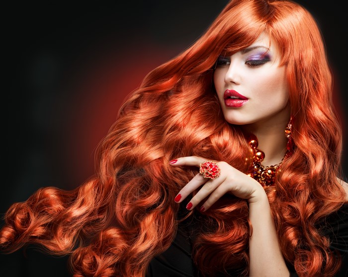 Redhead woman with voluminous wavy hair and jewelry