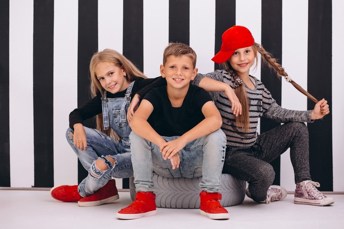 Three children sitting in front of a striped background