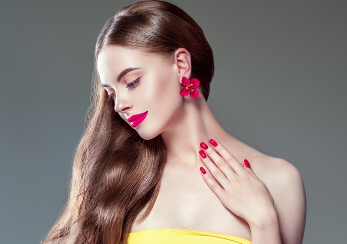 Woman with brown hair, red lips, and red nails