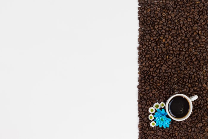 Coffee beans with a cup of coffee and flowers
