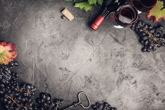 Grapes, Wine Bottle, and Glasses on Textured Surface