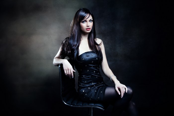 Brunette girl in a black dress sitting