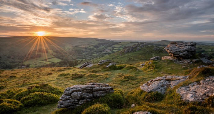 Sunrise over rolling hills with rocks in Devon, England