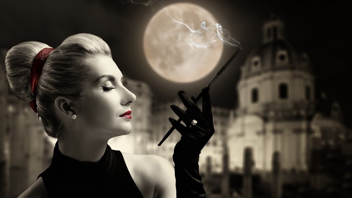 Woman smoking with moon and building in background