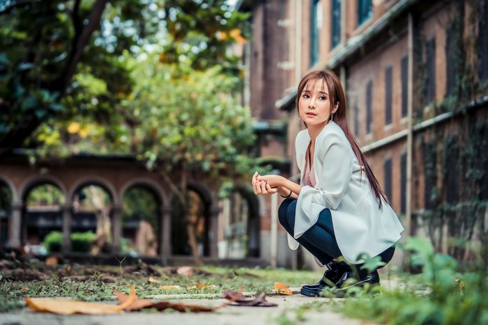 Asian woman with brown hair crouching outdoors