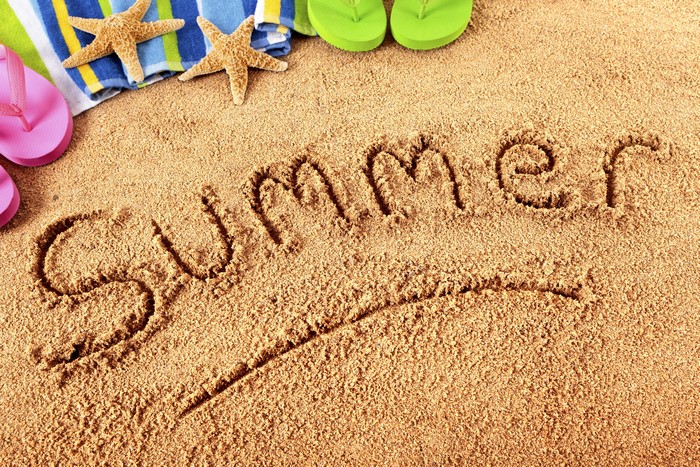 Summer written in sand with beach accessories