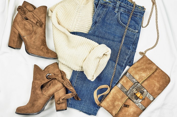 Brown boots, cream sweater, blue jeans, and brown handbag