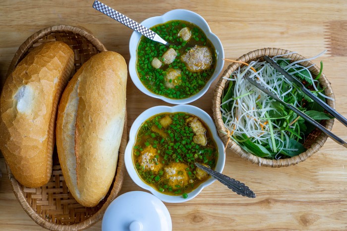 Two bowls of soup with bread and vegetables