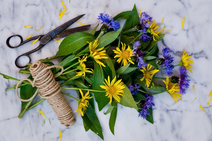 Bouquet of yellow and blue flowers with scissors and twine