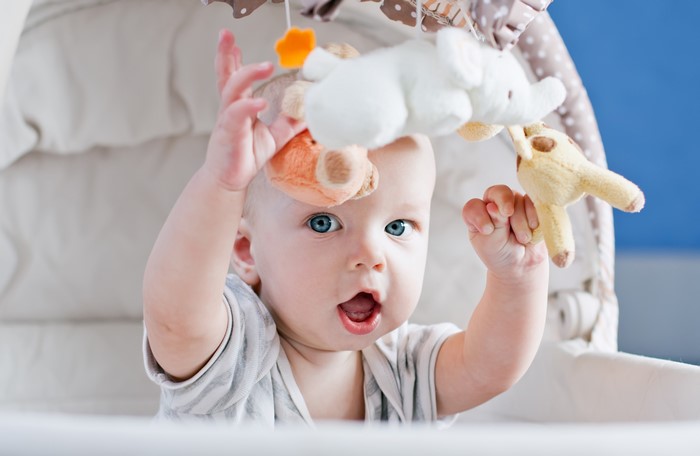 Baby reaching for toys on a mobile
