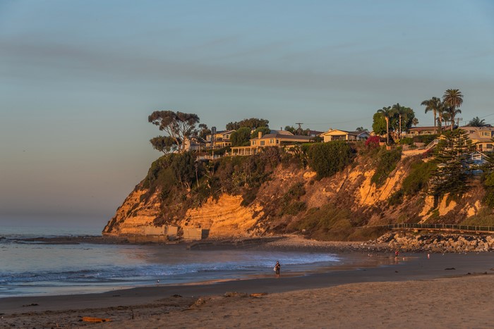 Houses on a cliff overlooking the ocean at sunset