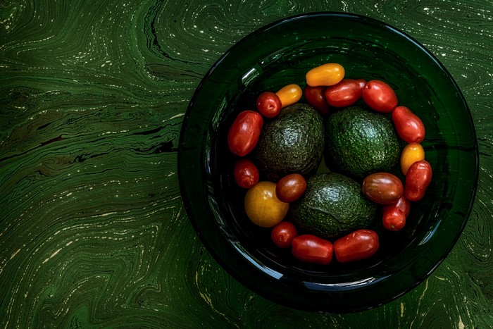 Avocado and cherry tomatoes in a green bowl