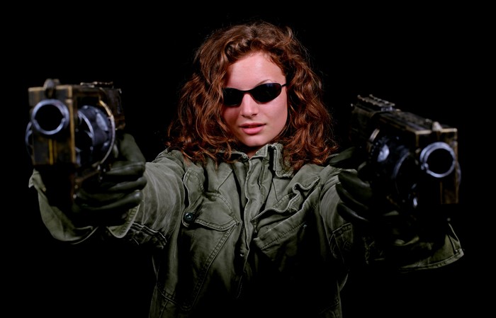 Woman with two pistols on black background
