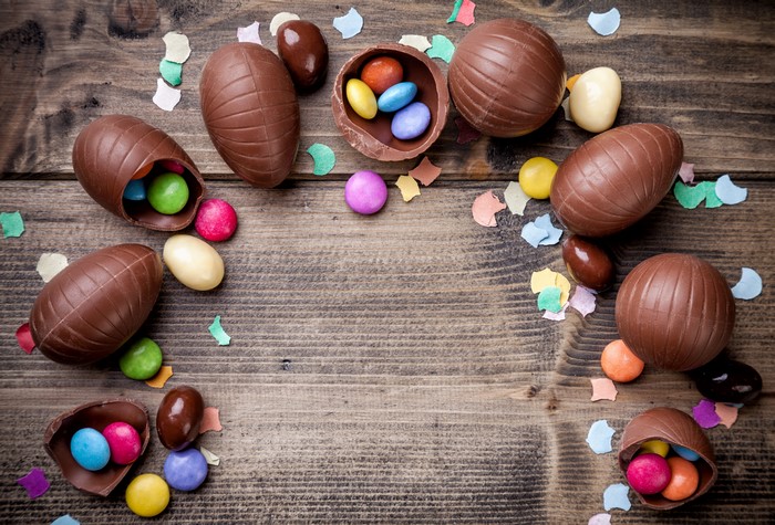 Easter chocolate eggs with candies on wood planks