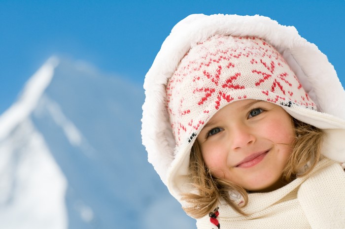Girl in winter hat and scarf with snowy mountain background