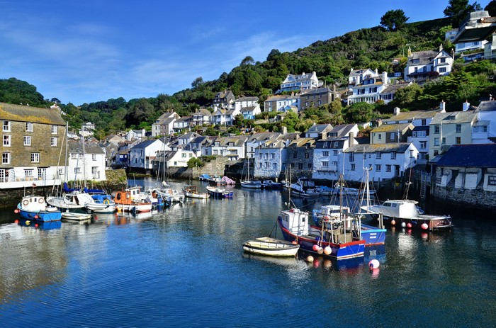 Boats in a harbor with houses on a hill in Polperro, Cornwall