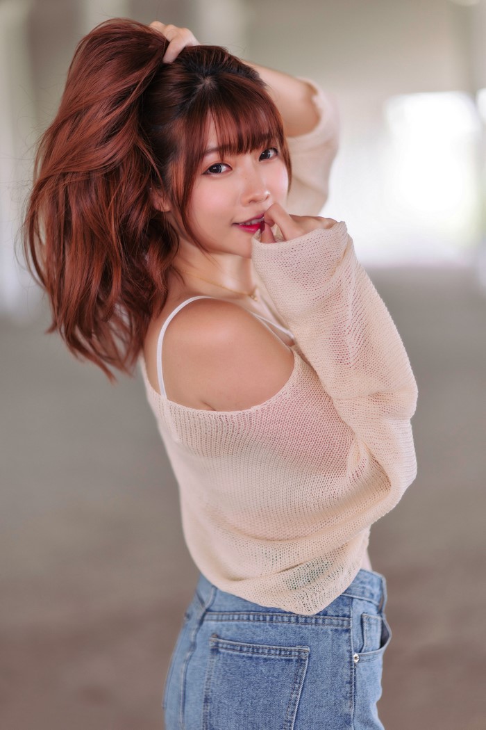 Asian woman with red hair in a beige sweater and jeans