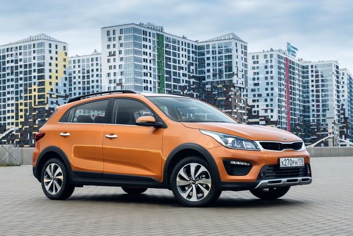 Orange KIA Crossover parked in front of modern buildings