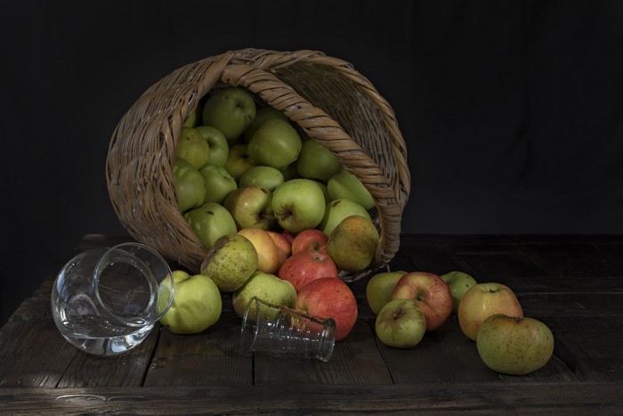 Apples spilling from a wicker basket onto wooden planks