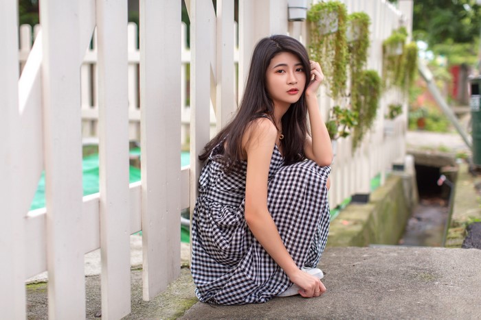 4K Asian Woman Sitting by White Fence