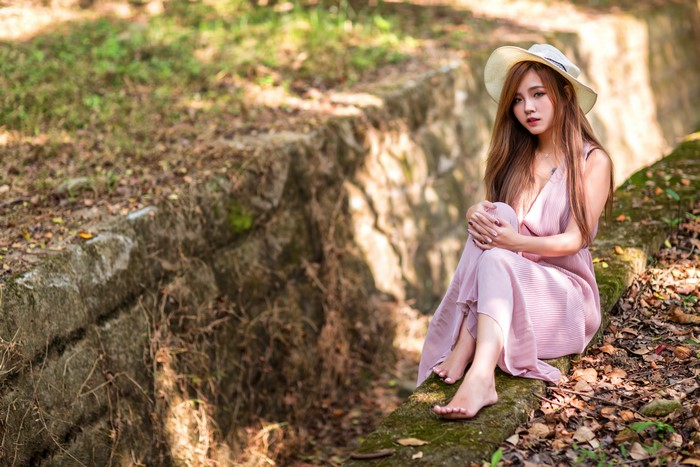 Asian woman wearing a hat and dress sitting
