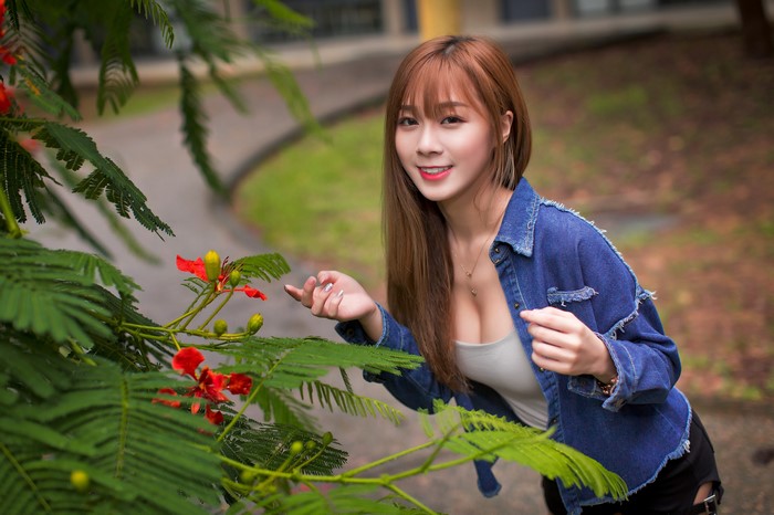 Asian woman in denim jacket near flowers