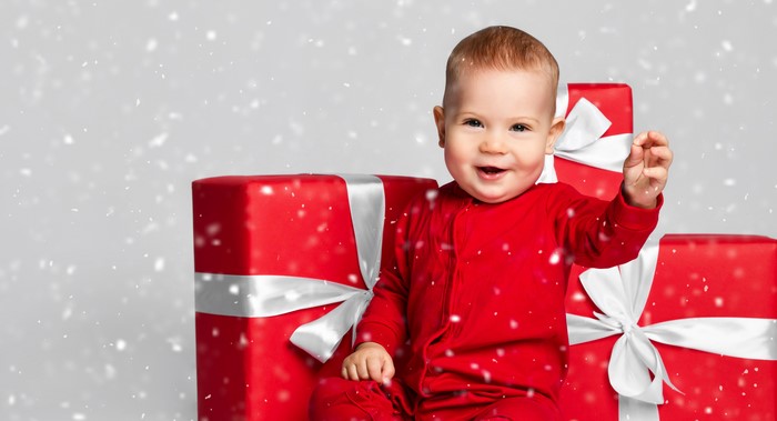 Baby in red pajamas with Christmas gifts