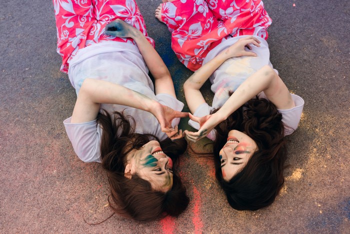 Two Asian women lying down with colorful makeup