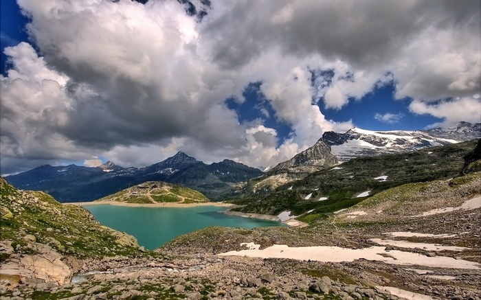 Turquoise lake and snow-capped mountains under cloudy sky