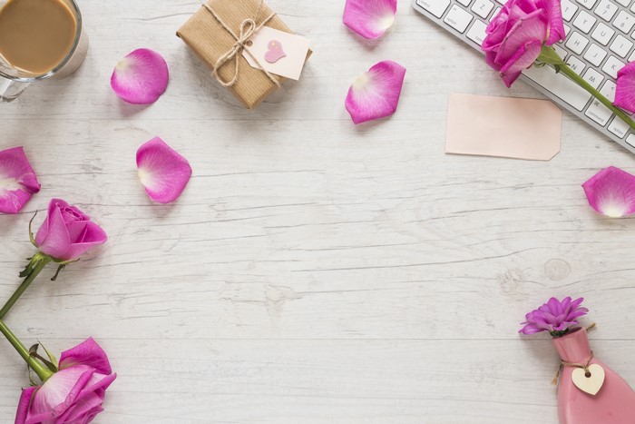 Pink roses, gift, coffee, and petals on a wooden table