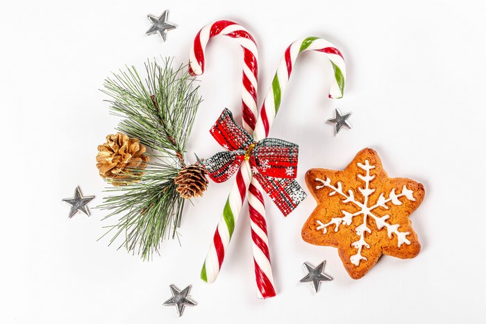 Christmas candy canes, pine branch, pine cones, gingerbread star cookie, and star decorations on a white background